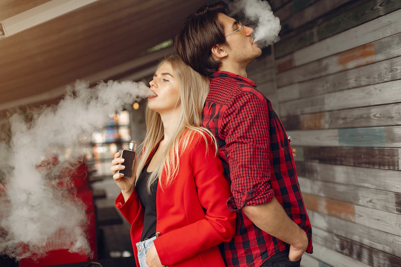 Stylish young couple with vape in a city, Disposable vapes and smokes, chargeable vape pen, Foodgod, mega, myle, Juul, Flum, suorin, puff, air bar, hide all these vapes and smokes are available.