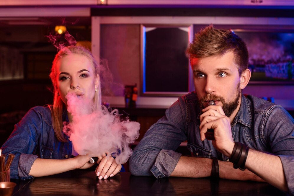 A man and woman smoking electronic cigarette in a vape bar, Stylish young couple with vape in a bar, vapes and smokes