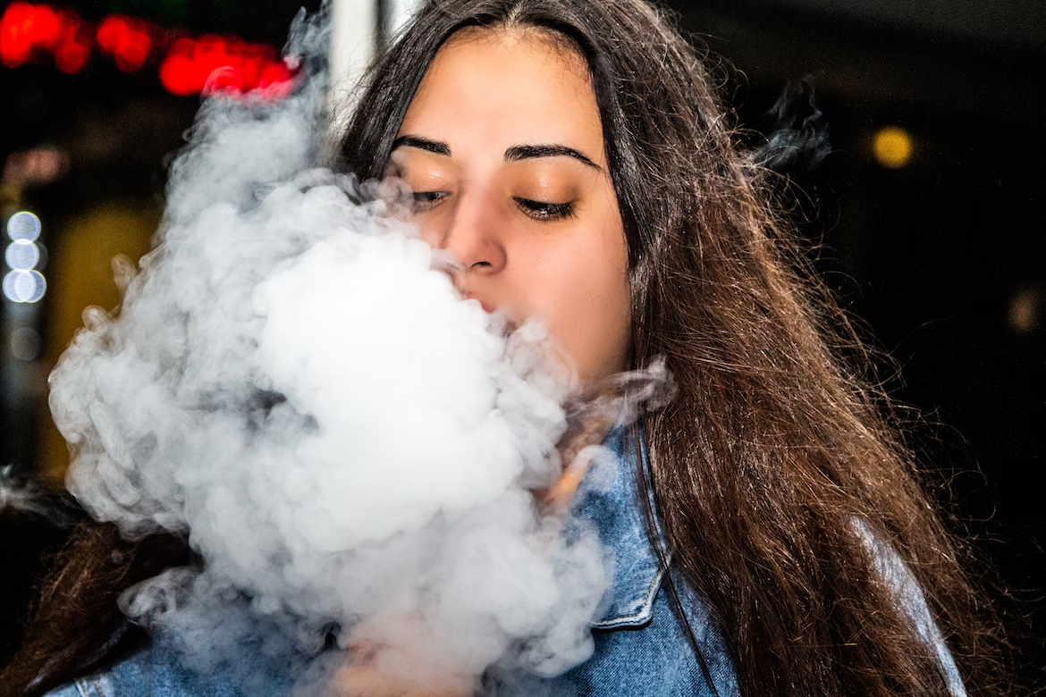 cute girl vaping in on a road, Reasons why people start Vaping ?Disposable vapes and smokes, chargeable vape pen, Foodgod, mega, myle, Juul, Flum, suorin, puff, air bar, hide all these vapes and smokes are available.